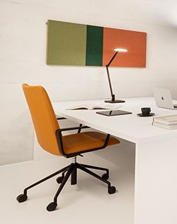 Arbeitsbereich mit Schreibtisch und Stuhl. An der Wand hängt ein Akustikpaneel mit CAVALLO PIU von Création Baumann.