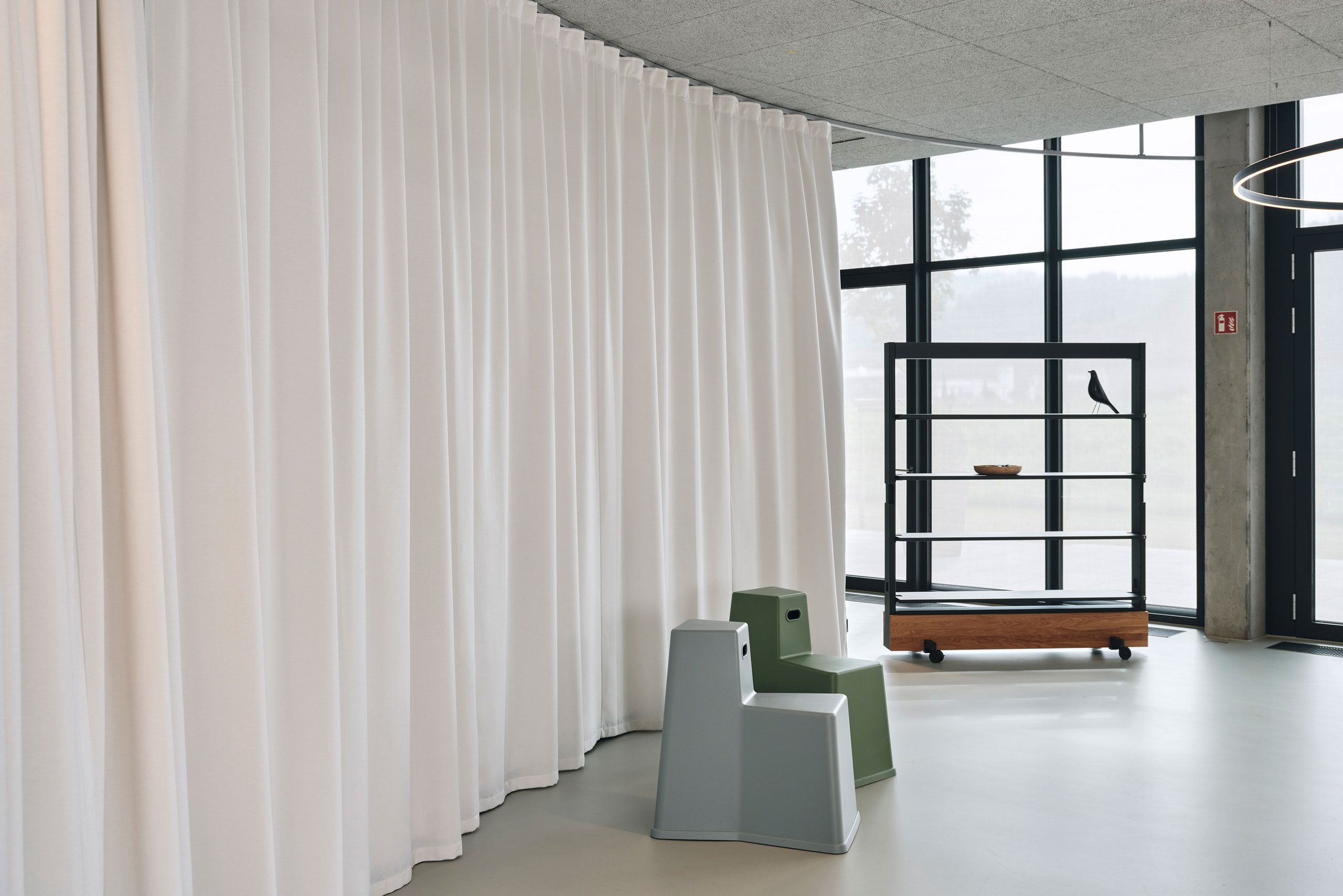 Ruhige Bürosituation mit wenig Möbel und viel Raum, auf einer Seite räumlich getrennt durch einen Akustiktrennvorhang.