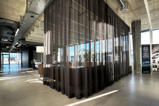 A black, semi-transparent curtain separates a seating area in an open-plan office.