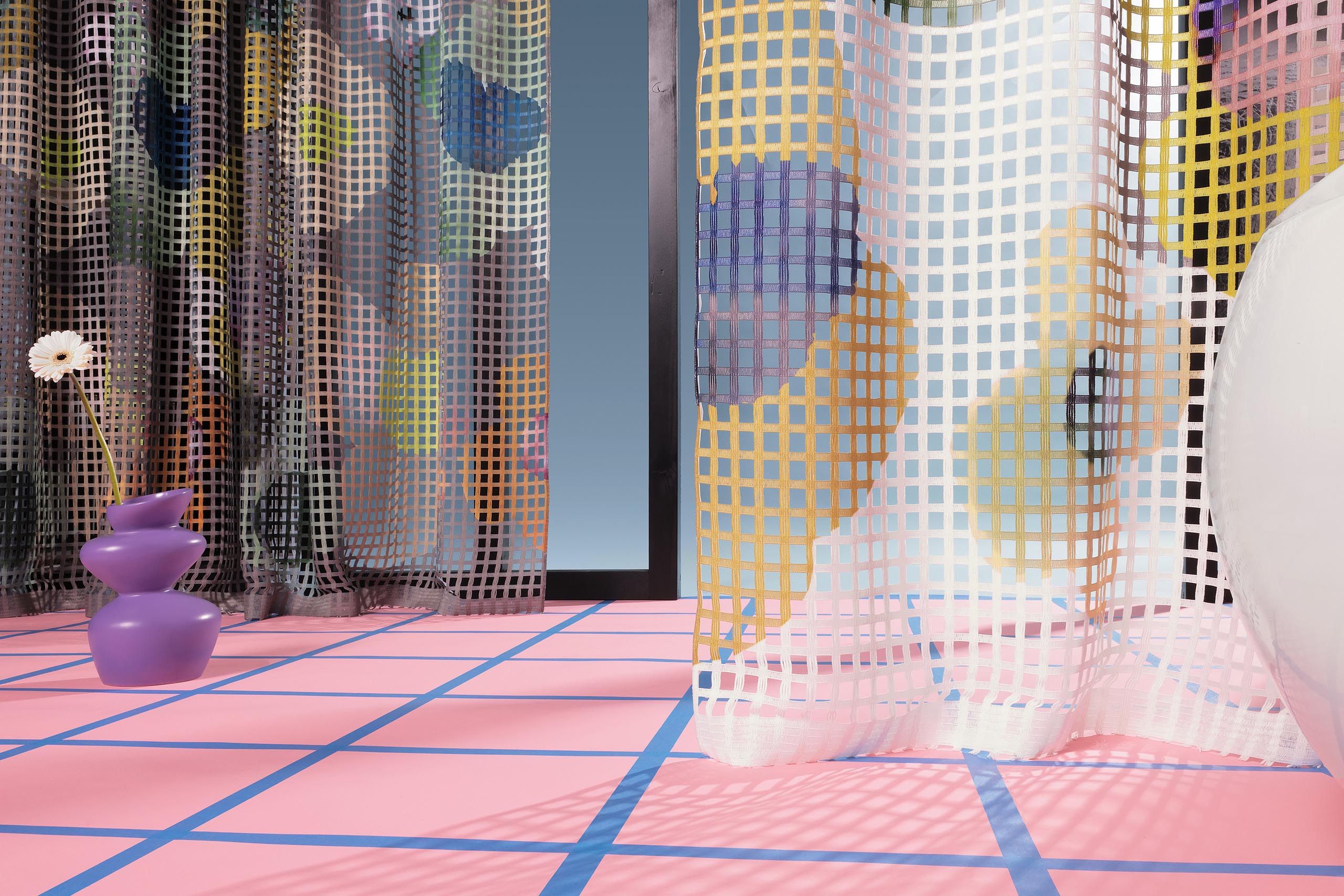 Transparenter Netz-Vorhangstoff von Création Baumann mit floralem Muster mit feiner Gitterstruktur, modern inszeniert in farbigem Design-Interior mit skulpturaler lila Vase und grafischem Boden.